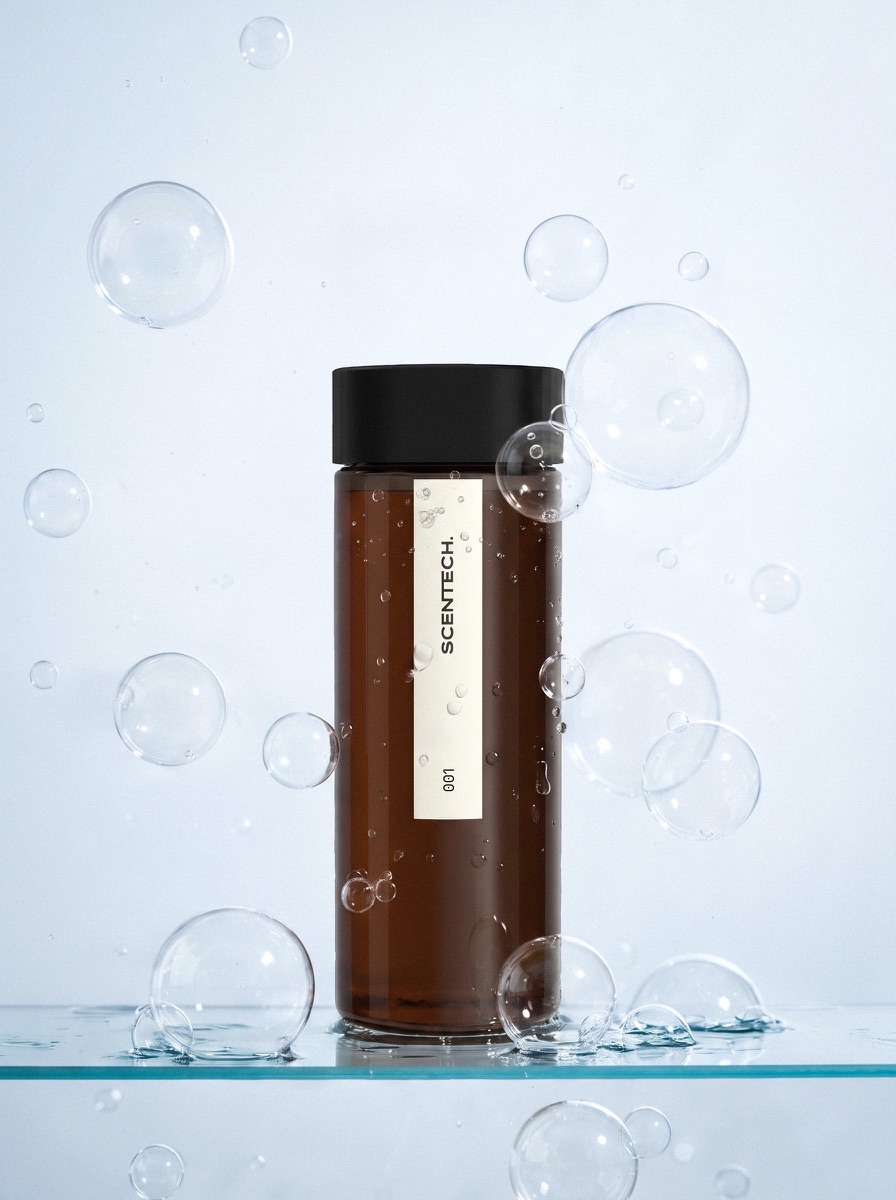 Two amber refill bottles of Scentech fragrance oil standing on a pale linen surface in low afternoon light